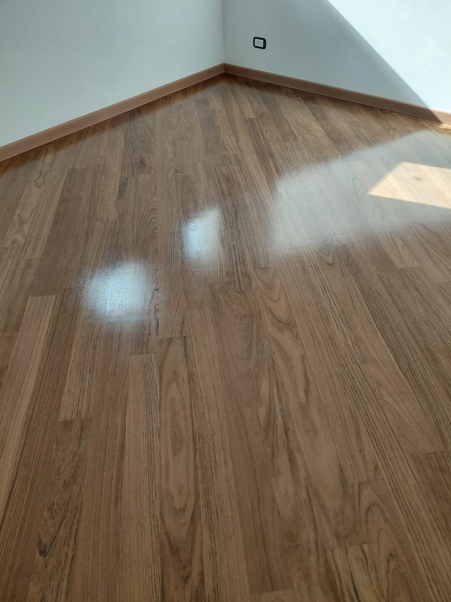 Listoni in teak lucidati a specchio in una stanza vuota