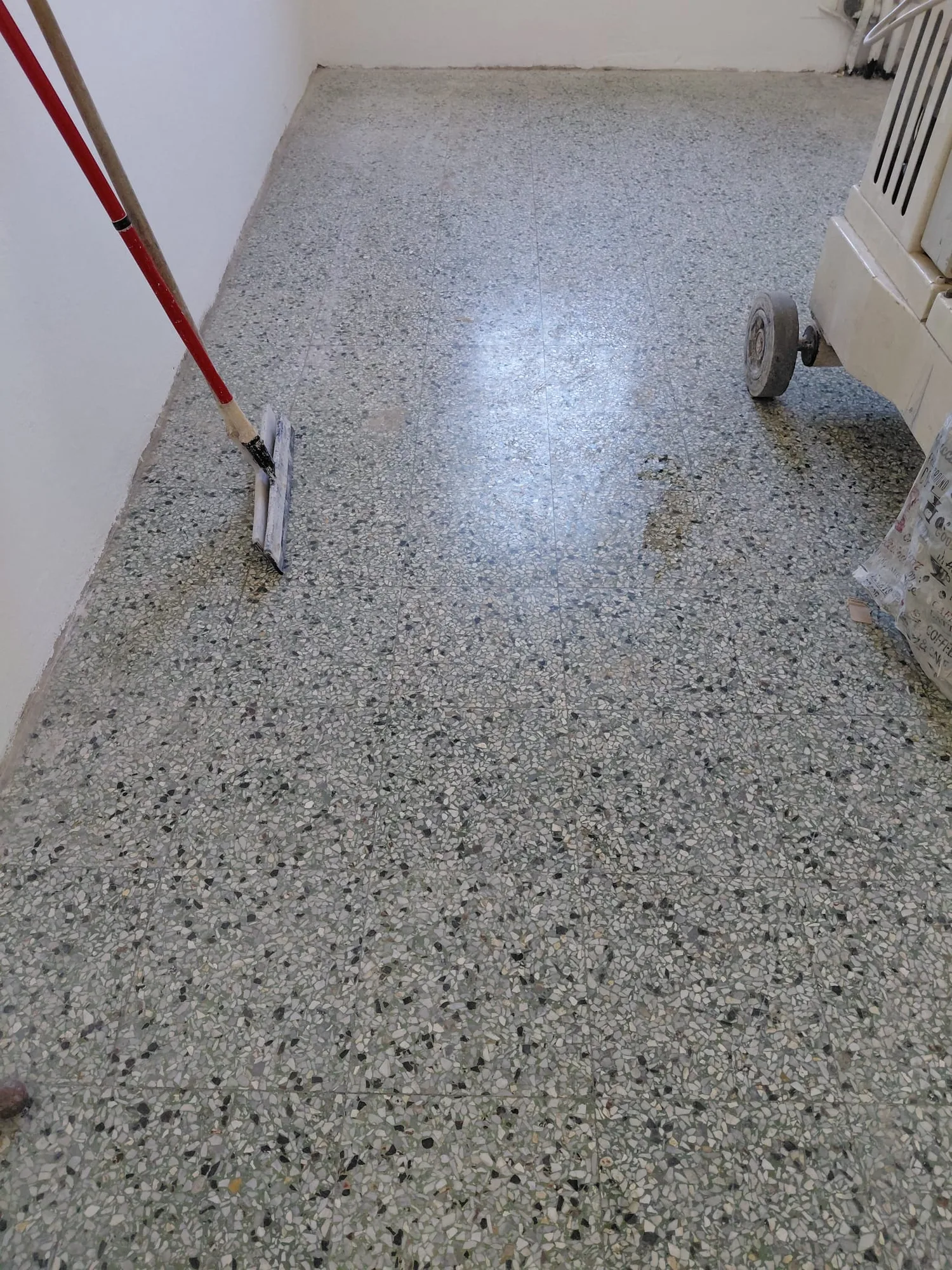 Graniglia verde ancora opaca, con la spatola per lo stucco e la levigatrice