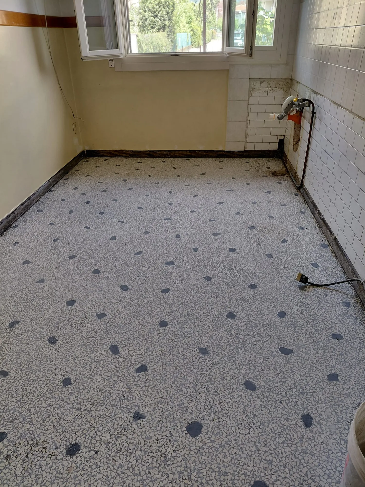Pavimento in terrazzo bianco e grigio opaco in una vecchia cucina, prima del lavoro