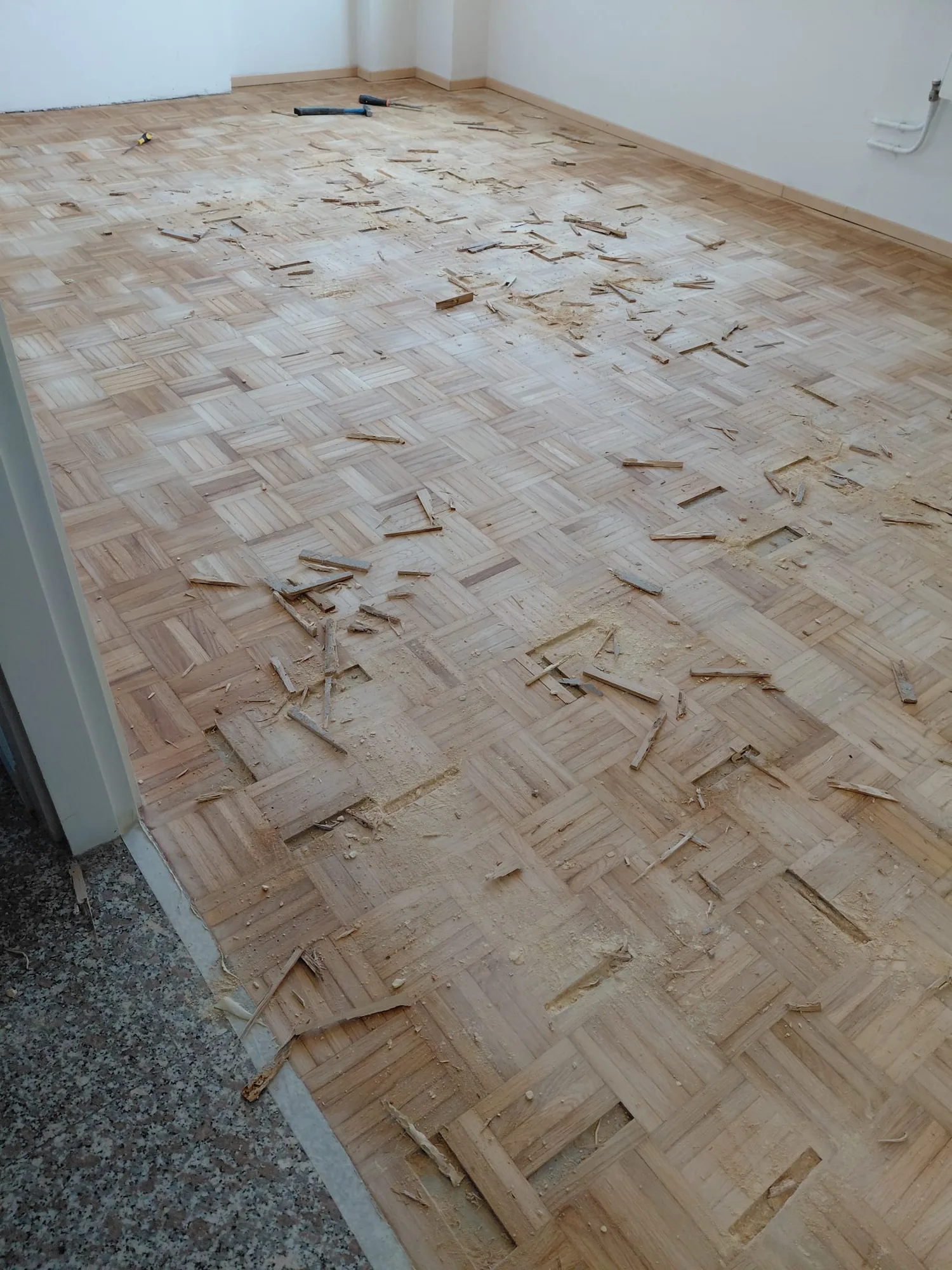 Parquet a mosaico con listelli sollevati da sistemare prima della levigatura