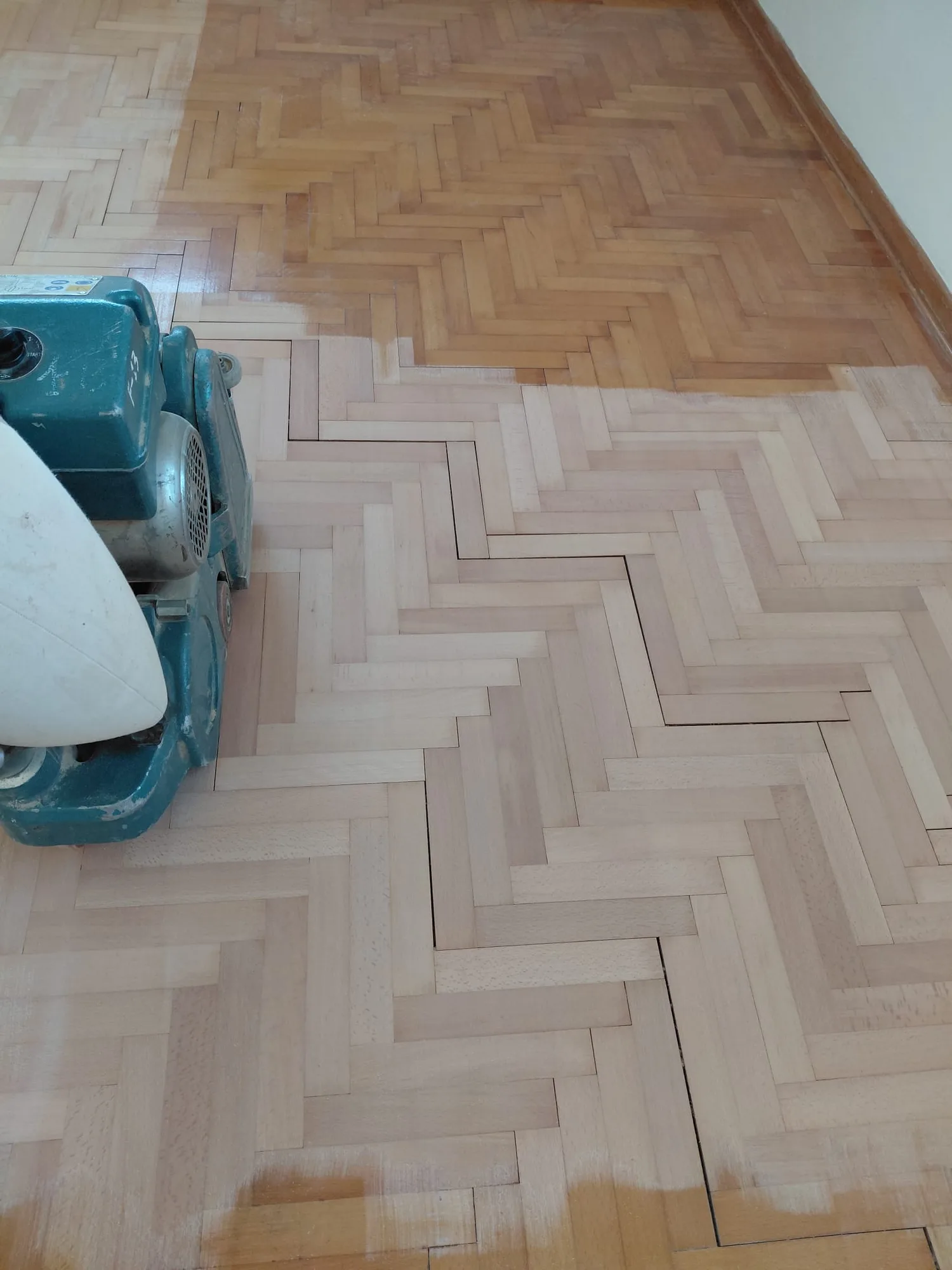 Spina di pesce in faggio a metà lavoro: la levigatrice ha riportato il legno al colore naturale