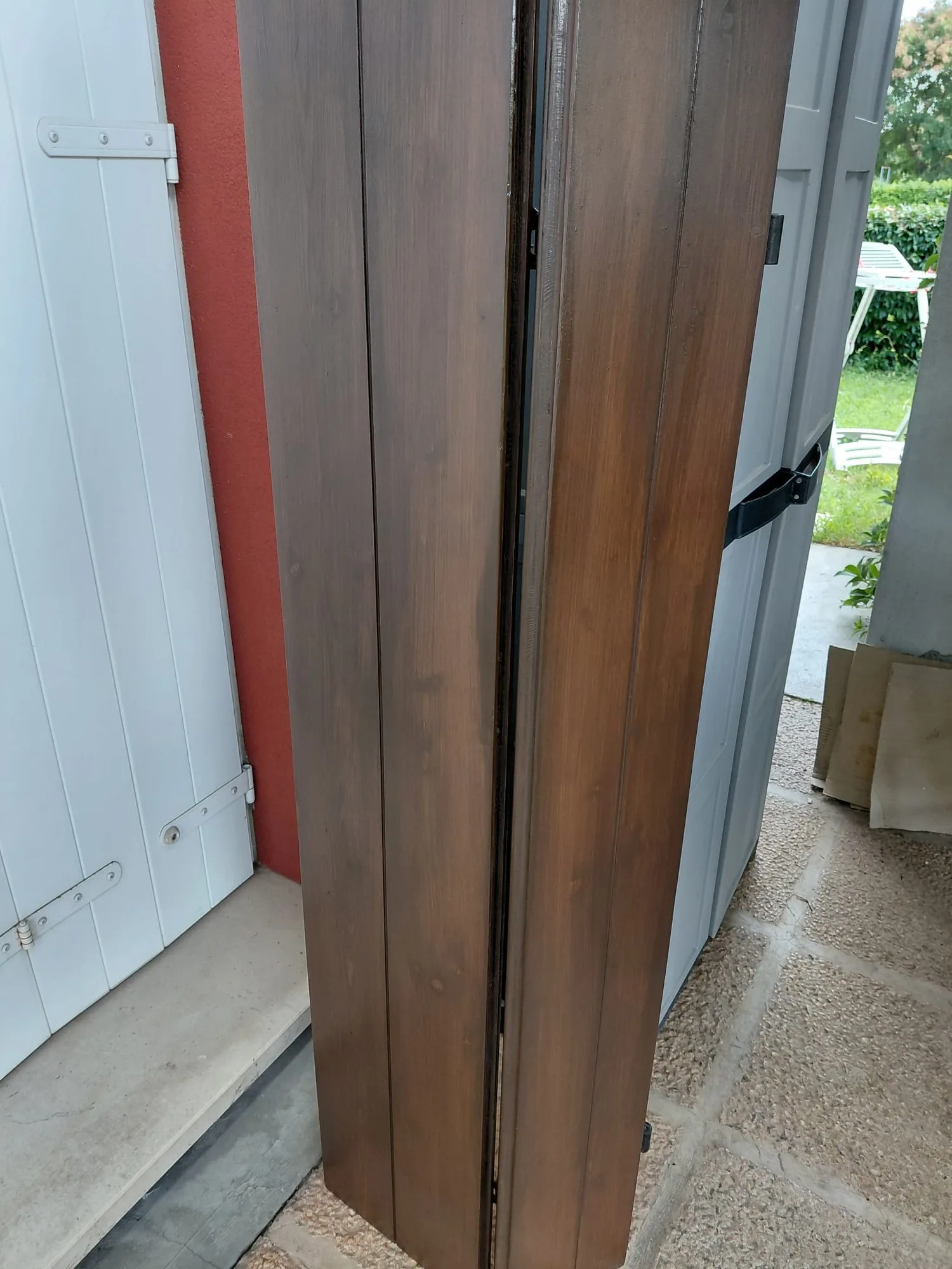 Scuri in legno restaurati, levigati e rifiniti con impregnante scuro, appoggiati davanti a casa