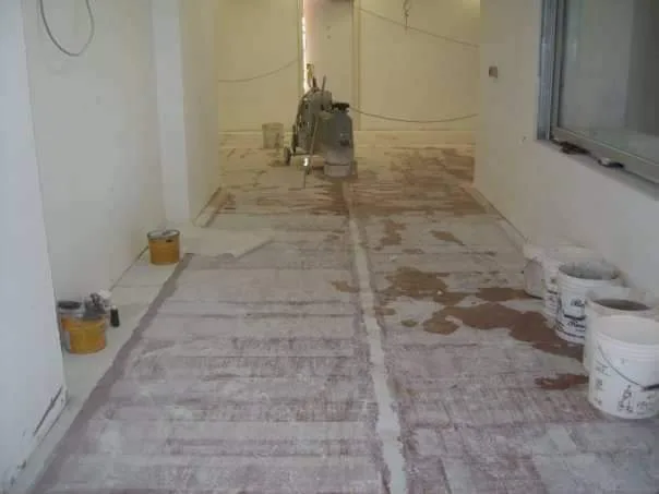 Corridoio in marmo in lavorazione, con levigatrice e secchi per lo stucco