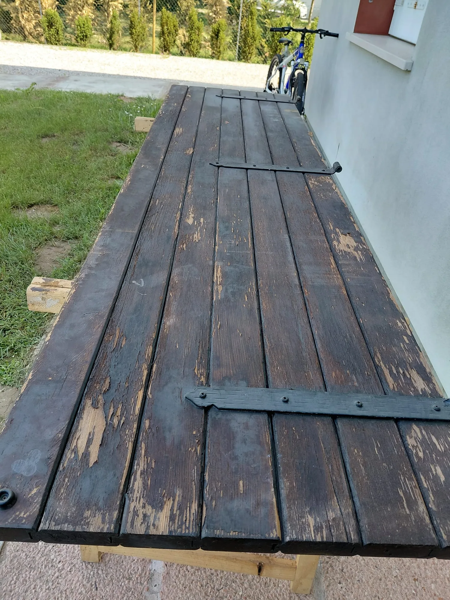 Scuro in legno con la vernice scura scrostata e le bandelle in ferro, prima del restauro